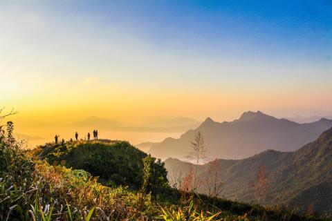 Group of people standing on a hilltop at sunset