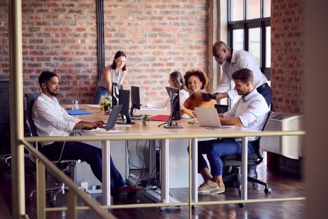 Colleagues talking around a desk in an open office space